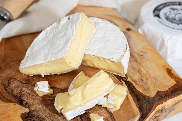 Torpenhow Three Hills Brie, a soft round organic cheese on a rustic wooden cheese board
