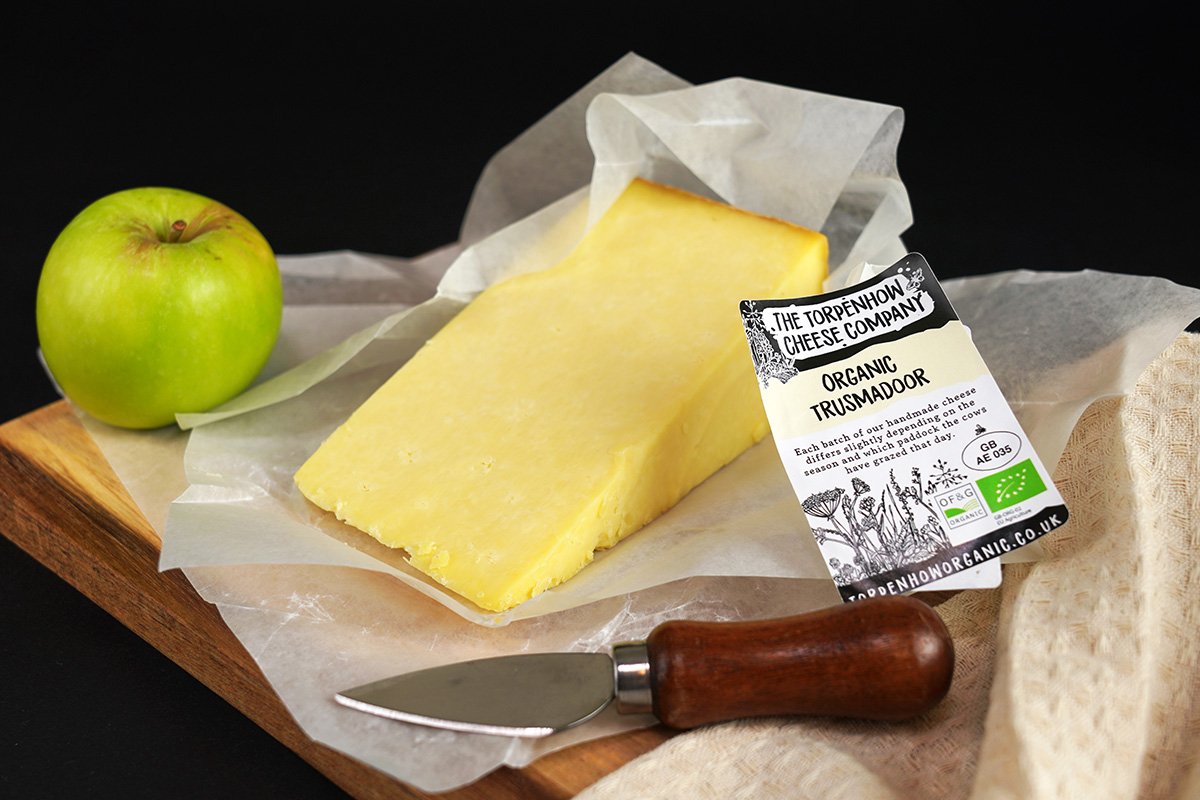 Trusmadoor cheese on a cheeseboard with knife and apple - a Lancashire style creamy, crumbly organic cheese